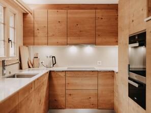 A compact kitchen with wooden cabinets, a stainless steel sink, and a built-in oven. - Giferblick Appartement/Fewo, Dusche und Bad, WC 6-Bettwohnung by Interhome (Gstaad)