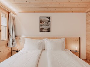A bedroom with a wooden headboard, a bed with white linens, two bedside tables with lamps, and a framed picture on the wall. - Giferblick Appartement/Fewo, Dusche und Bad, WC 6-Bettwohnung by Interhome (Gstaad)