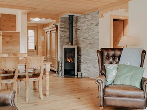 A cozy living room with a fireplace, wooden furniture, and a stone wall. - Giferblick Appartement/Fewo, Dusche und Bad, WC 6-Bettwohnung by Interhome (Gstaad)