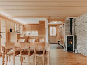 A wooden interior with a dining area, kitchen, and a fireplace. - Giferblick Appartement/Fewo, Dusche und Bad, WC 6-Bettwohnung by Interhome (Gstaad)