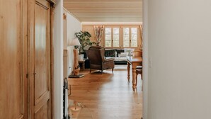 Ein Flur, der in einen Wohnbereich mit Holzboden, einem Sofa, einem Tisch und einer Lampe führt.