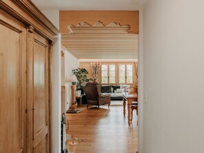 A hallway leading to a living area with wooden flooring, a sofa, a table, and a lamp. - Giferblick Appartement/Fewo, Dusche und Bad, WC 6-Bettwohnung by Interhome (Gstaad)