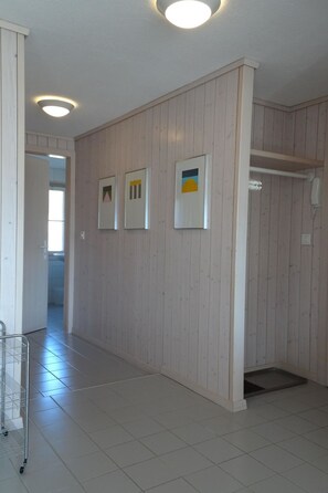 A hallway with wooden panel walls, a metal cart, and a phone on a hook. - Monique Nr. 1 Appartement/Fewo, Dusche oder Bad, WC 4-Bettwohnung by Interhome (Gstaad)