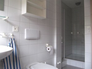Een badkamer met toilet, wastafel, douche en handdoekrek.