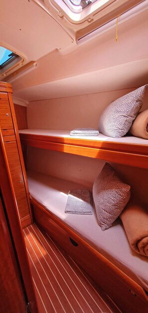 Eine Holzhütte mit Holzmöbeln, einem Fenster und einem Stockbett mit gemusterten Kissen.