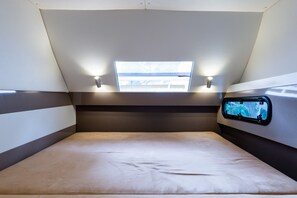 A modern, compact room with a bed, a window with a view, and a mounted TV. - Sun-Kissed Sailing Adventure in the Ionian Islands, Lefkada (Lefkada)