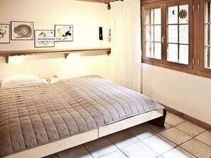 A bedroom with a bed, a window with curtains, and wall art. - Drive Appartement/Fewo, Dusche oder Bad, WC 4-Bettwohnung by Interhome (Gstaad)