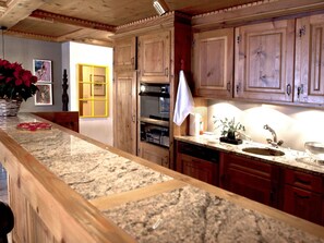 Una cocina con armarios de madera, encimera de granito, horno integrado y un lavamanos.