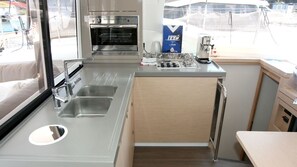 A compact kitchen with a sink, stove, and oven. - Sun-Kissed Sailing Adventure in Northern Croatia (Punat)