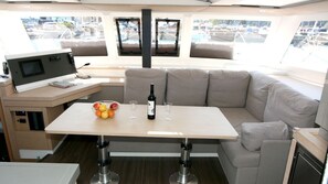 A modern interior with a dining area, a sofa, a television, and a view of the marina. - Sun-Kissed Sailing Adventure in Northern Croatia (Punat)