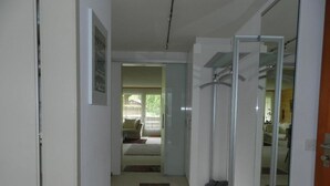 Ein Flur mit Teppich, einer Glastür und Blick in ein Wohnzimmer mit Sofa und Fenster.