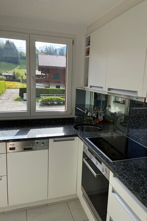 Une cuisine moderne avec des armoires blanches, un comptoir en granit et un lave-vaisselle encastré.