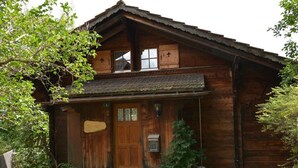 Una casa di legno con un portone, un piccolo portico e un vialetto in pietra che conduce all'ingresso.