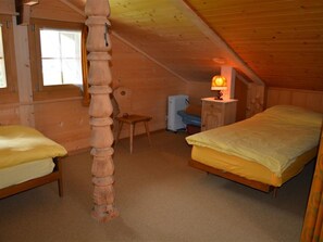 A bedroom with two beds, a chair, a radiator, and a lamp. - Marmotte, Chalet Appartement/Fewo, Dusche, WC 4-Bettwohnung by Interhome (Lauenen b. Gstaad)