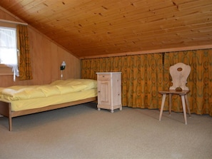 A bedroom with a single bed, a nightstand, a dresser, and a chair. - Marmotte, Chalet Appartement/Fewo, Dusche, WC 4-Bettwohnung by Interhome (Lauenen b. Gstaad)