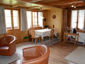 A cozy cabin interior with a dining table, two leather chairs, a small kitchen area, and a wooden ceiling. - Marmotte, Chalet Appartement/Fewo, Dusche, WC 4-Bettwohnung by Interhome (Lauenen b. Gstaad)