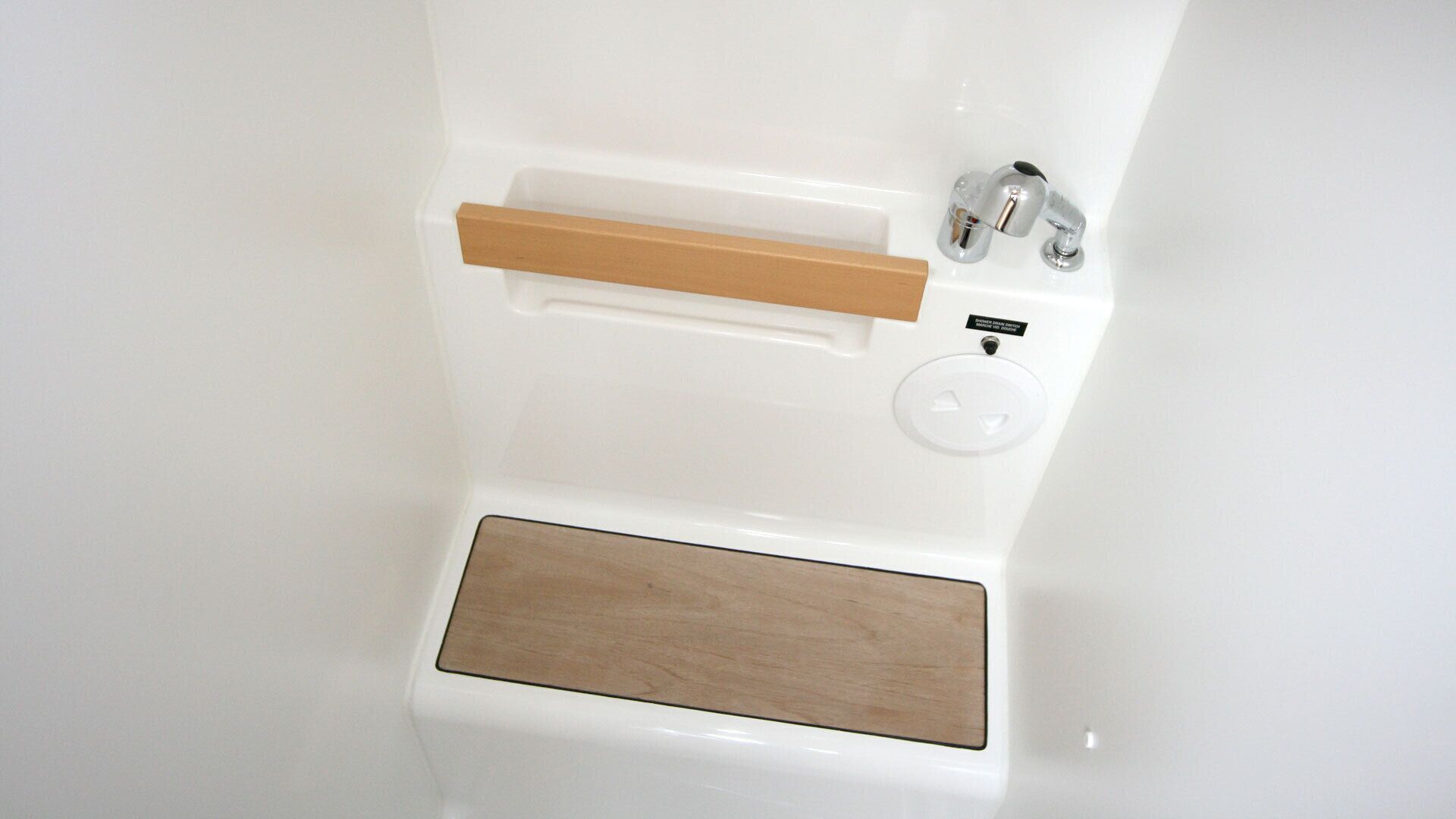 Eine Badewanne mit Holzablage, Wasserhahn und Armatur.