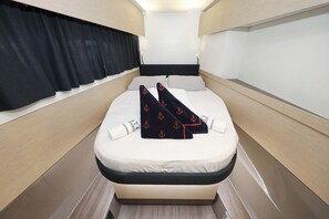 A narrow cabin with a bed, a window with curtains, and a headboard. - Sun-kissed Sailing Adventure in Istria, Croatia (Pomer)