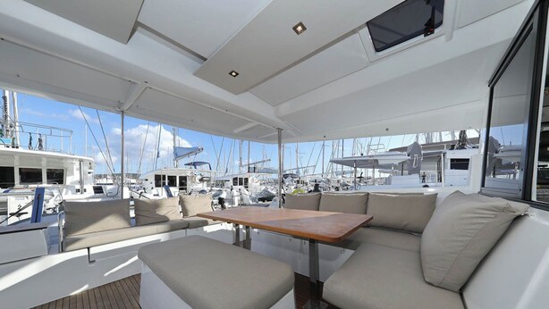 Das Interieur einer Yacht mit Essbereich, gepolsterten Sitzgelegenheiten und Blick auf den Yachthafen.
