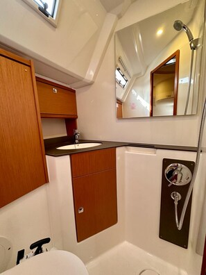 Ein kleines Badezimmer mit Waschbecken, Spiegel und Dusche.