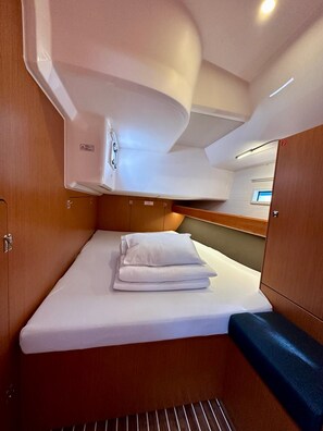 Une petite cabine comprenant un lit, un petit coin salon et une fenêtre.