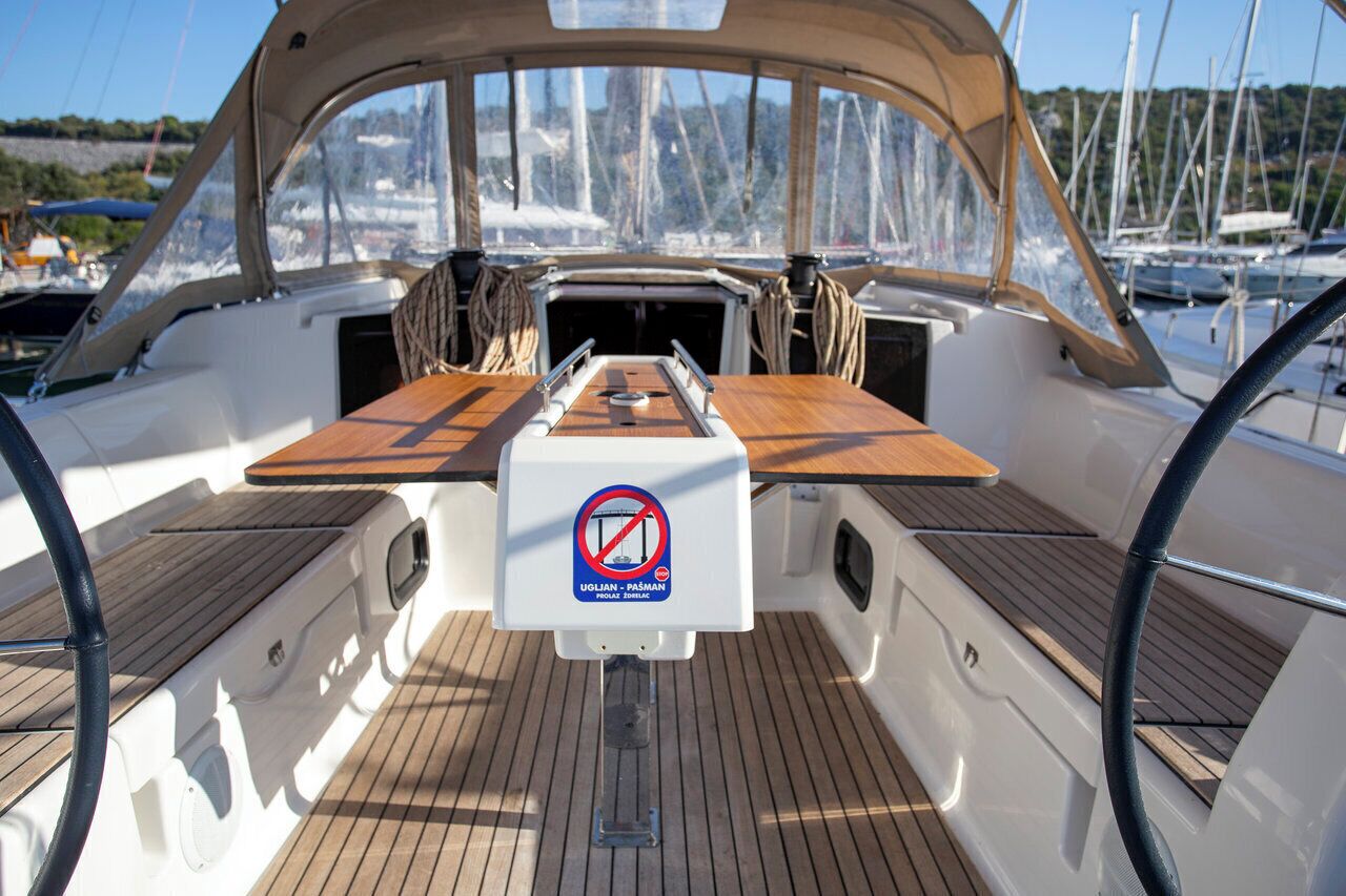 A boat deck with a central table, a no smoking sign, and a view of the marina.