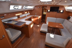 A compact interior with a dining area, seating, a small kitchen, and a TV. - Sun-Kissed Sailing Adventure in Northern Croatia (Punat)