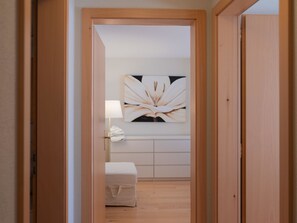 Ein Flur mit Holztürrahmen, einer weißen Bank, einer Wandleuchte und einem großen Blumenbild.