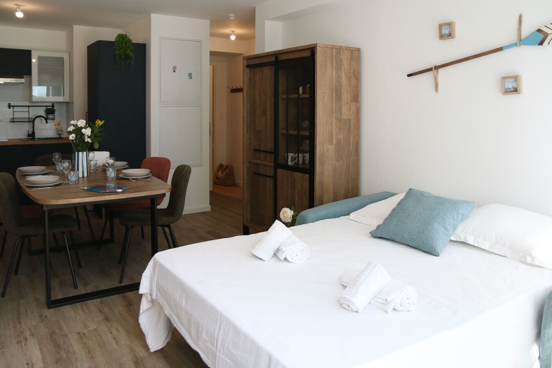 Ein Hotelzimmer mit einem Bett, einem Esstisch mit Stühlen, einer Küchenzeile und einem Kleiderschrank.
