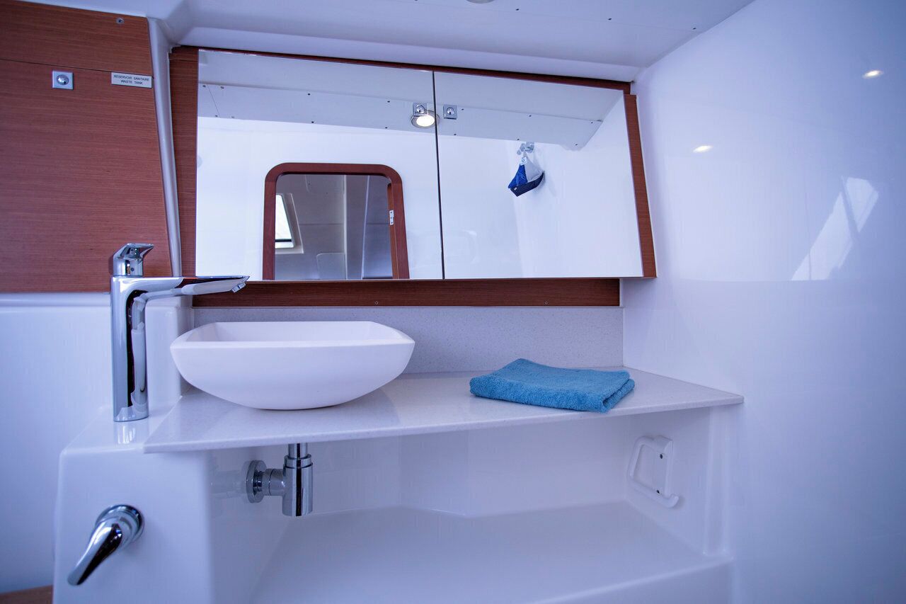 Un baño con un lavabo blanco, espejo y una toalla azul.