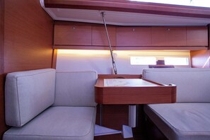 A compact interior with a wooden cabinet, a small table with a map, and two cushioned seating areas. - Sun-Kissed Sailing Adventure in Northern Croatia (Mali Lošinj)
