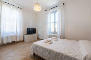 Ein Schlafzimmer mit Bett, Fernseher, Heizkörper und Vorhängen.