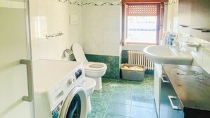Uma lavanderia compacta com máquina de lavar, vaso sanitário e pia.