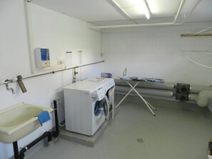 A clinical or laboratory setting with a washing machine, a sink, and an ironing board. - Suzanne Nr. 18 Appartement/Fewo, Dusche oder Bad, WC 5-Bettwohnung by Interhome (Gstaad)