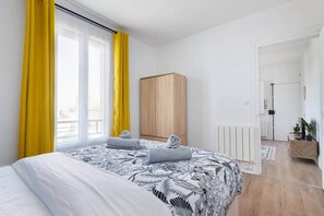 Ein Schlafzimmer mit Bett, Schrank, Heizkörper und einer Tür zu einem anderen Raum.