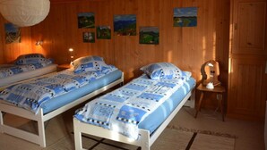 Ein Zimmer mit zwei Betten, Holzwänden und mehreren Bildern.
