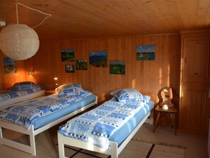 Ein Zimmer mit zwei Betten, Holzwänden und mehreren Bildern.