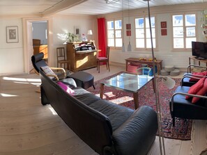 Una sala de estar con sofá, mesa de centro, televisor y piano.