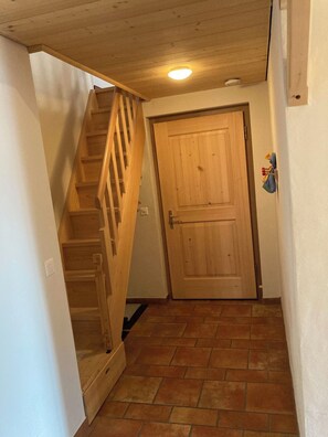 A wooden staircase leading to a door with a tiled floor.