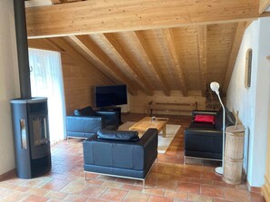 A cozy living room with a fireplace, leather sofas, a television, and a wooden ceiling. - Fichte (Sulliger) Appartement/Fewo, Dusche oder Bad, WC 6-Bettwohnung by Interhome (Gstaad)