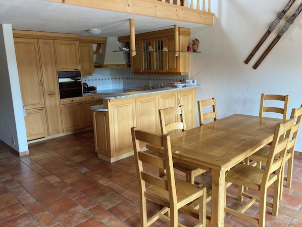 A kitchen with wooden cabinets, a dining table, and chairs.