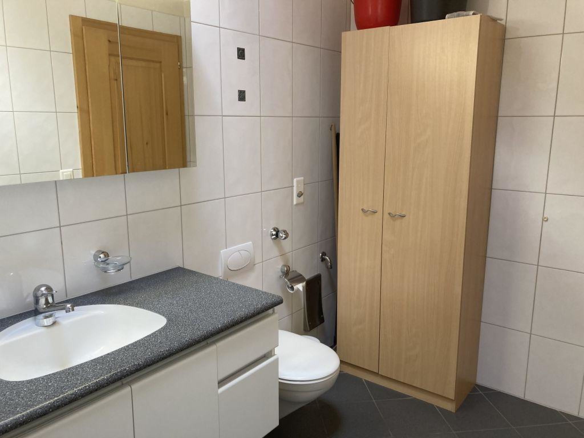 Een badkamer met een houten kast, een wastafel en een toilet.