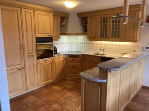 A kitchen with wooden cabinets, a built-in oven, a sink, and a countertop. - Fichte (Sulliger) Appartement/Fewo, Dusche oder Bad, WC 6-Bettwohnung by Interhome (Gstaad)