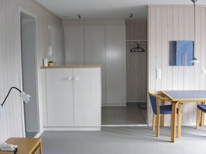 A room with a wooden table, chairs, a wardrobe, a hanging coat rack, and a painting on the wall. - Arlette Nr. 30 Appartement/Fewo, Dusche oder Bad, WC 2-Bettwohnung by Interhome (Gstaad)