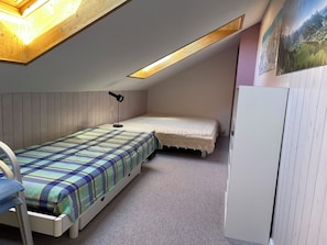 A small, single-bed room with a slanted ceiling, a desk, and a wardrobe. - Arlette Nr. 30 Appartement/Fewo, Dusche oder Bad, WC 2-Bettwohnung by Interhome (Gstaad)