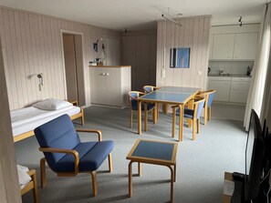 A compact room with a bed, a desk, a chair, a small table, and a kitchenette. - Arlette Nr. 30 Appartement/Fewo, Dusche oder Bad, WC 2-Bettwohnung by Interhome (Gstaad)