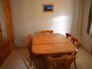 A rectangular wooden table with six chairs, a framed picture on the wall, and wooden paneling on the walls. - Jacqueline 11 Appartement/Fewo, Dusche oder Bad, WC 6-Bettwohnung by Interhome (Gstaad)