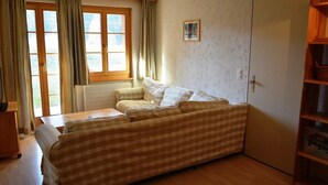 A room with a checkered sofa, a wooden table, a window with curtains, and a wardrobe. - Jacqueline 11 Appartement/Fewo, Dusche oder Bad, WC 6-Bettwohnung by Interhome (Gstaad)