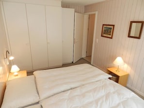 Habitación de hotel con cama, mesitas de noche, armario y puerta que da a otra habitación.