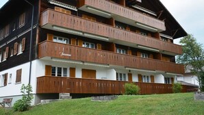 Un immeuble à plusieurs étages doté de balcons, avec l’inscription « Fusanne » sur la façade, et une pelouse devant.